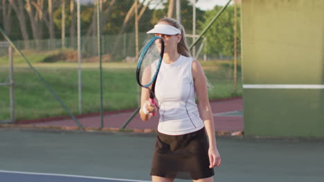 playing tennis on outdoor court, woman wearing visor and athletic outfit