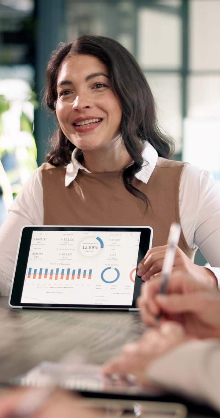 Empresária Apresentando Dados Financeiros em Tablet em Reunião no Escritório