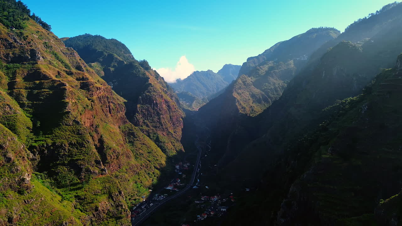 Residential area among the huge mountains. A highway crosses the village in the rocks. Madeira, Portugal top view.