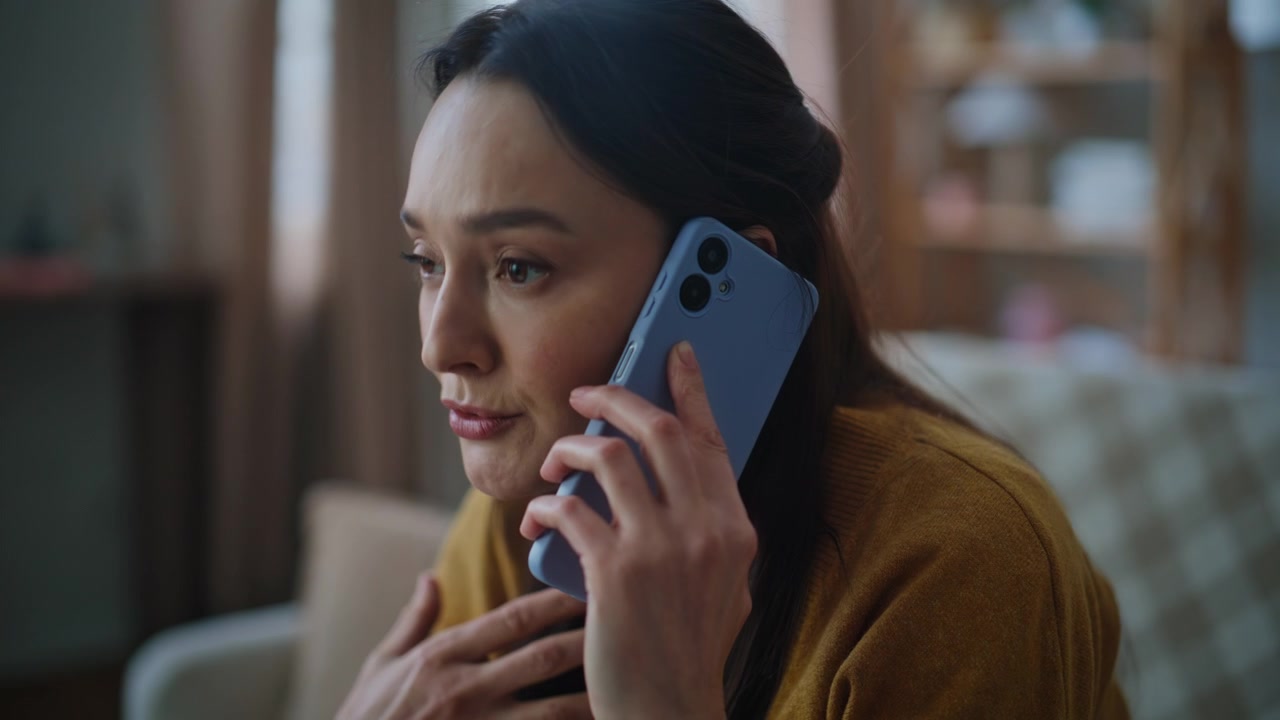 Displeased brunette talking cellphone sitting couch closeup. Woman calling