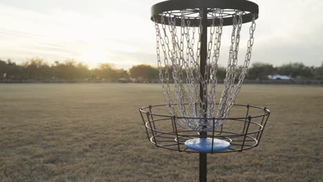 maakte disc golf putt in het ochtendlicht van een prachtige zonsopgang | schijfgolfspeler haalt vervolgens frisbee uit de kooi van de schijfgolfmand