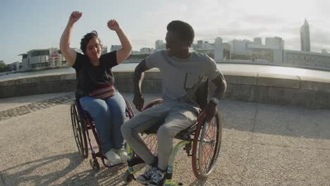 Cheerful-couple-dancing-using-wheelchairs-at-quay