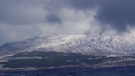 dark clouds moving over the high mountains covered with snow in scotland