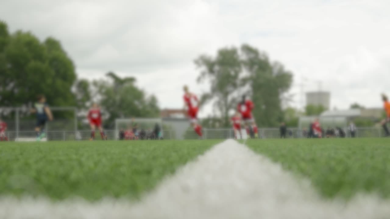 Fodbolddommer fløjter for at starte kampen mellem kvindelige fodboldhold i sportstøj på banen.