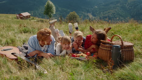 fröhliche familie, die gras liegt und picknick auf der wiese macht. sommerferien zusammen.