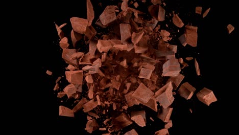 super slow motion of rotating group of raw chocolate pieces on black background.