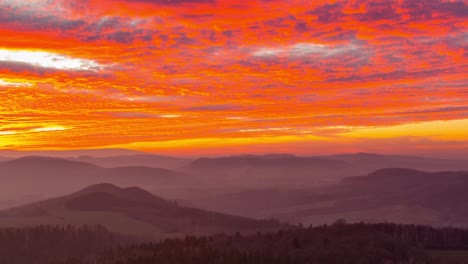 The-beautiful-red-orange-sunset-over-the-low-mountains-of-Ostrzyca-Proboszczowicka,-Poland---time-lapse