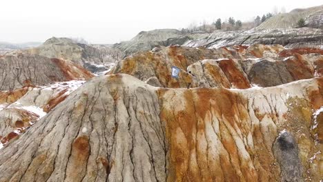 person holding flag on colorful mountainous quarry in winter