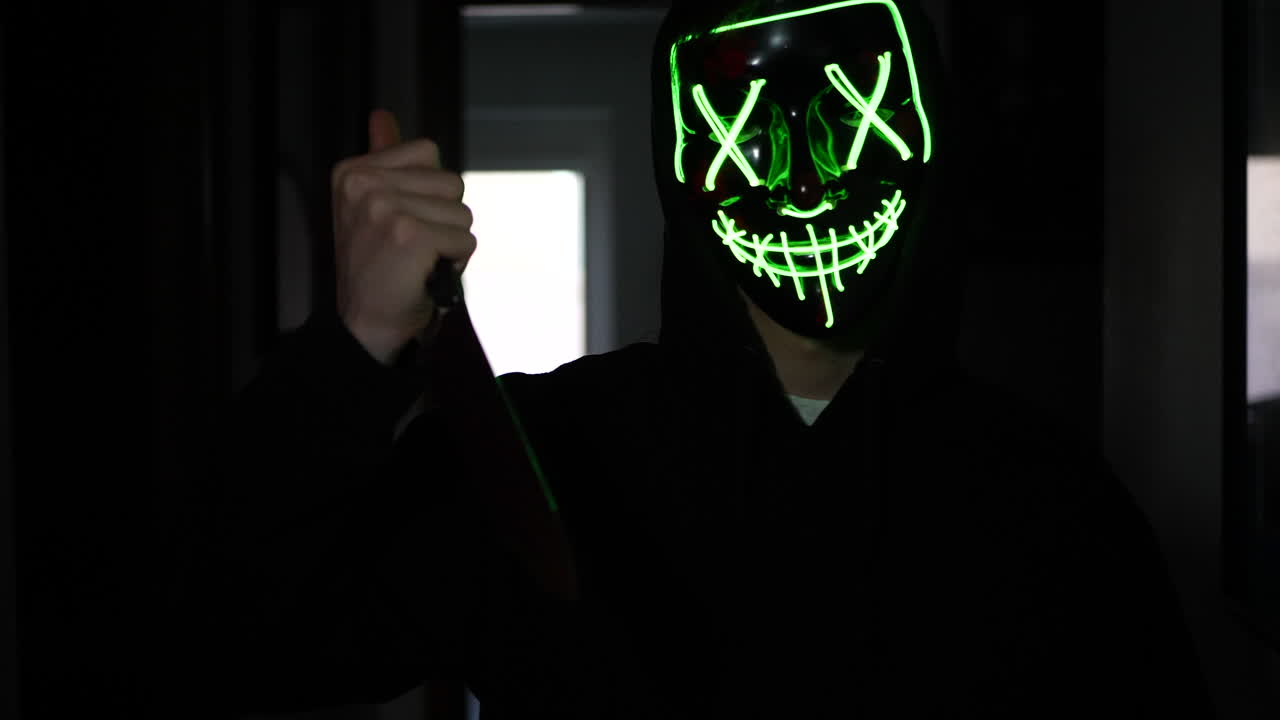 un asesino aterrador con una máscara genérica de halloween persiguiendo a una víctima de asesinato asustada con un cuchillo en cámara lenta