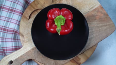 la mano de una mujer con un guante de goma coloca tomate, pimienta y pepino en un plato vacío en una mesa.