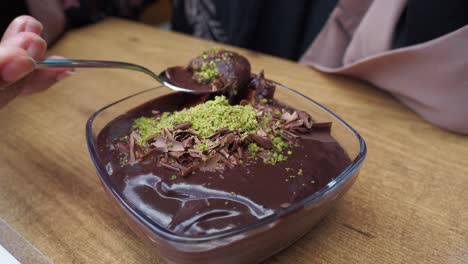 woman eating chocolate pudding with pistachios