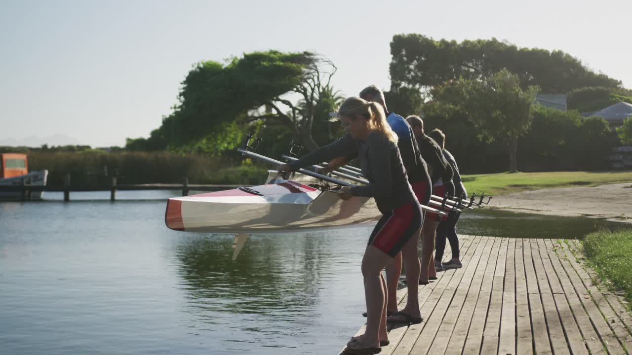 Squadra di canottaggio composta da quattro uomini e donne anziani caucasici che calano la barca nel fiume