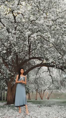 woman in a blue dress under a flowering tree