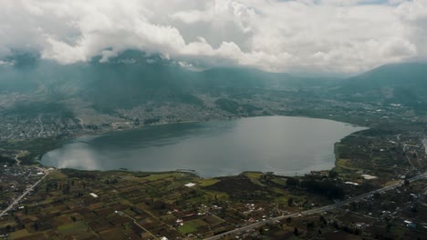 Laguna-De-San-Pablo-With-Imbabura-Volcano-Against-Cloudy-Sky-In-Otavalo,-Ecuador---Drone-Shot