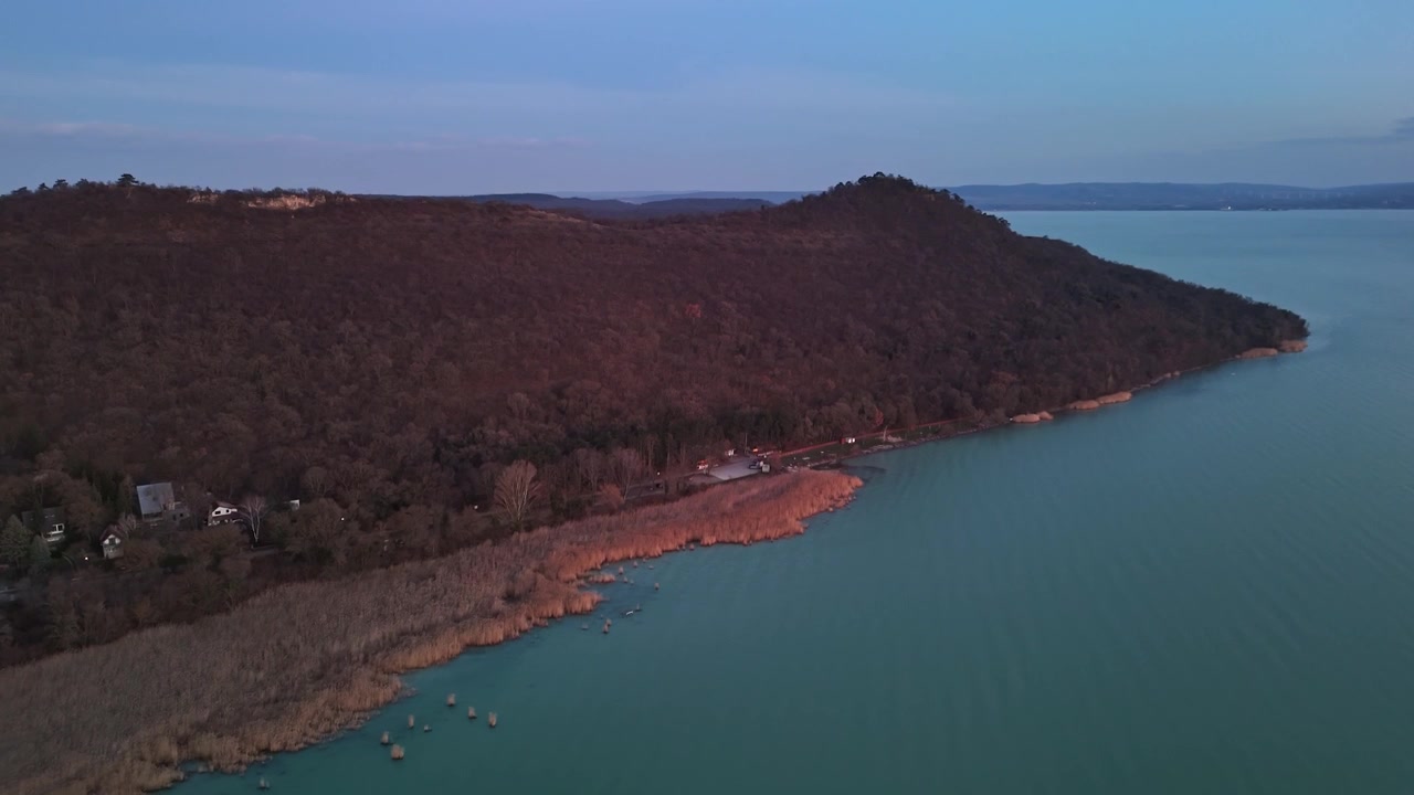 Sulla penisola di Tihany, in Ungheria, la costa del Lago Balaton e le colline boscose appaiono al crepuscolo in un paesaggio tranquillo visto da una prospettiva a volo d'uccello sopra il villaggio.