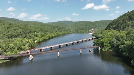 aerial rising shot of suspension footbridge over james river in virginia surrounded by green idyllic mountains in summer