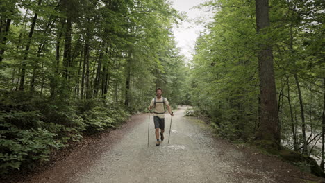 un joven excursionista caminando por un sendero forestal entre los árboles deciduoud