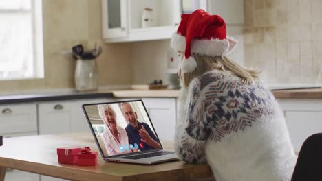 Caucasian-woman-wearing-santa-hat-on-laptop-video-chat-during-christmas-at-home