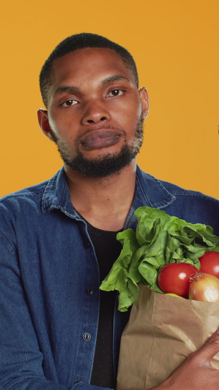 Homem afro-americano segurando um saco de papel com vegetais frescos