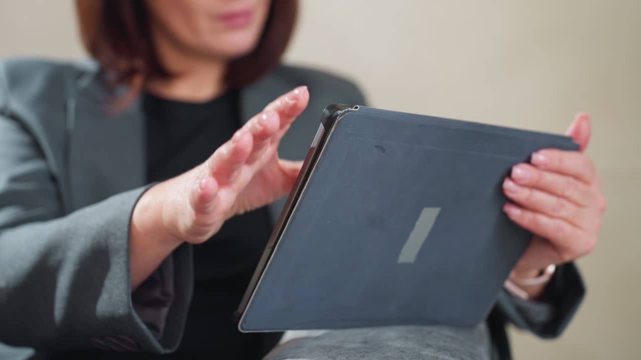 Confident businesswoman in suit holding digital tablet while reading content during work meeting or remote session, showcasing modern professional lifestyle and digital workplace engagement