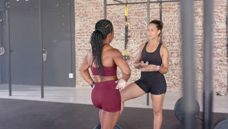 women in gym discussing workout routine, preparing for fitness training session