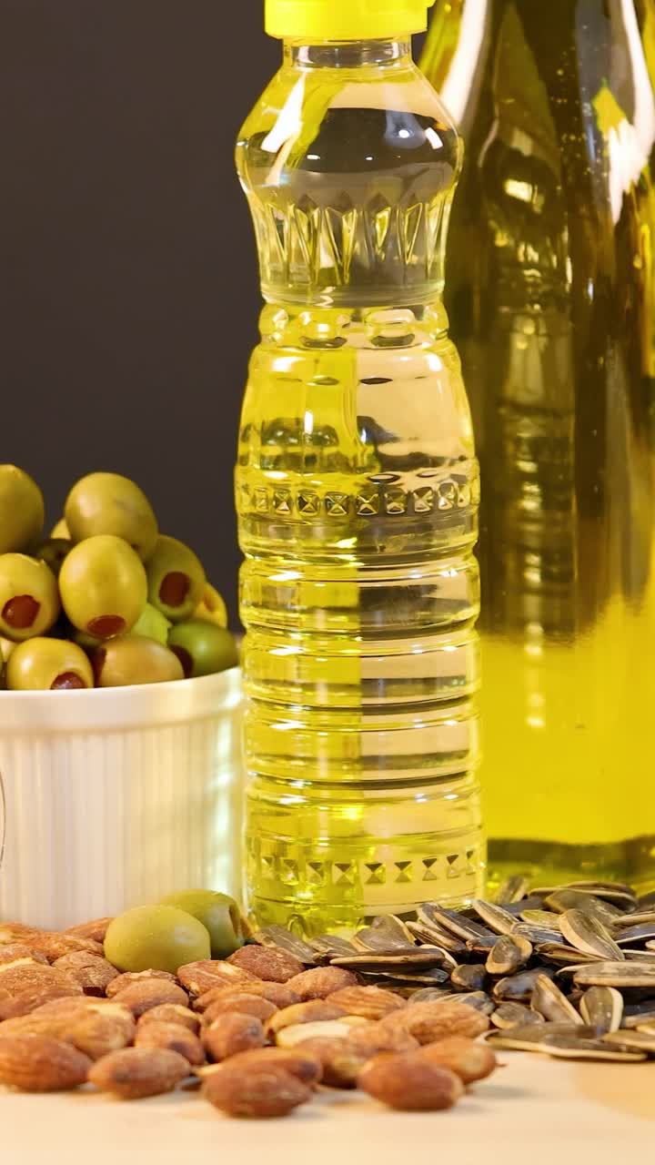 Una varietà di grassi sani, inclusi avocado, oli, noci e olive, disposti su una superficie di legno.