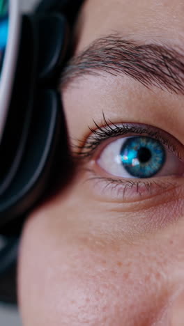 close-up of a person wearing headphones and glasses with blue eyes