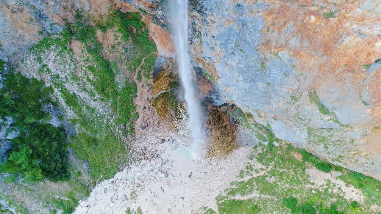 Aerial pull back and rising view of cascading waterfall down a rocky mountain facade, Rinka waterfalls, Slovenia