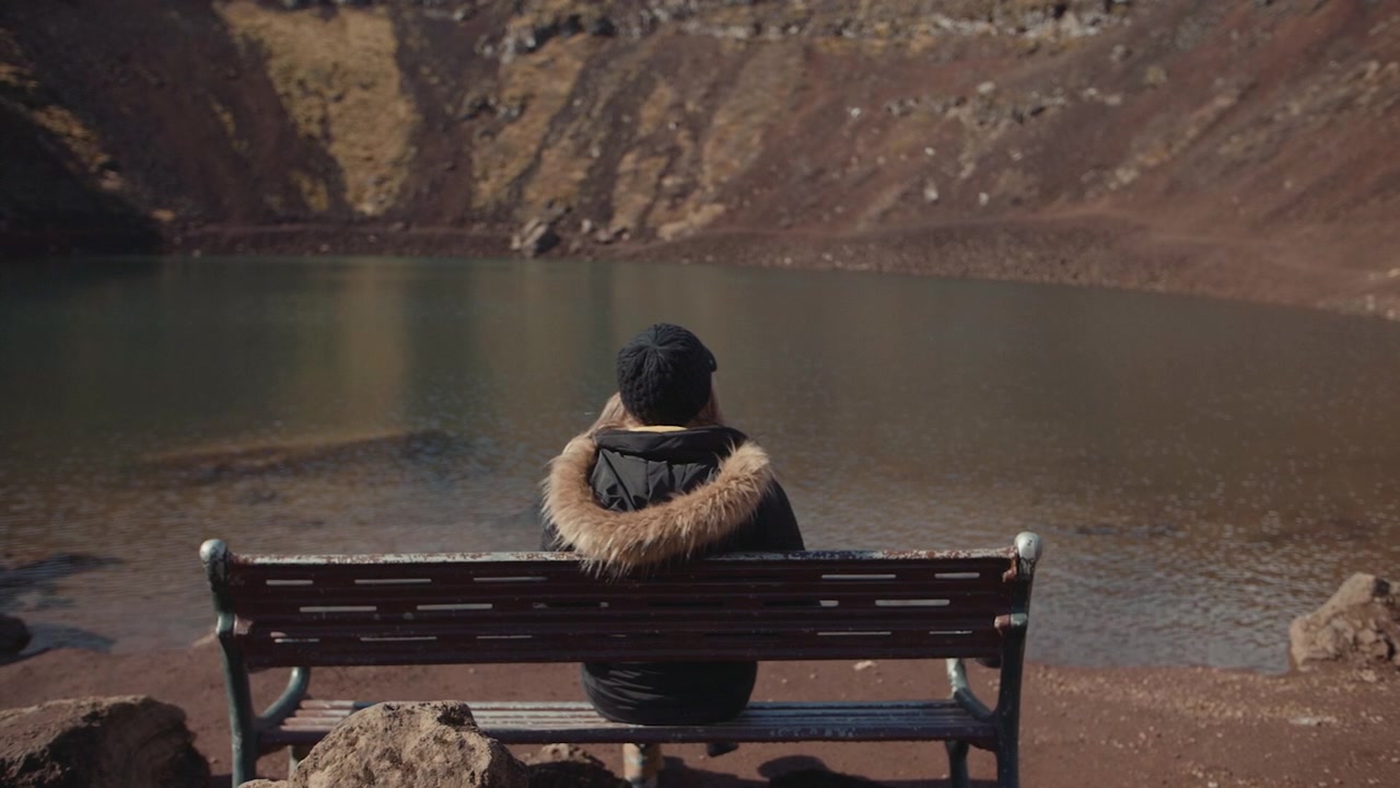 Persona seduta su una panchina che si affaccia sul Crater Lake