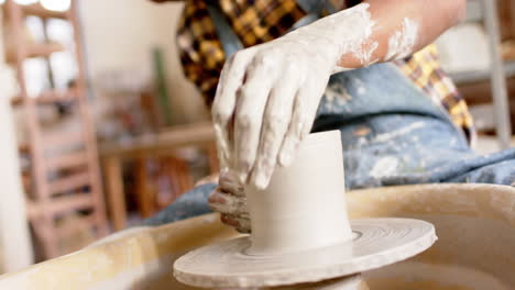 african american male potter using potter's wheel in pottery studio, slow motion