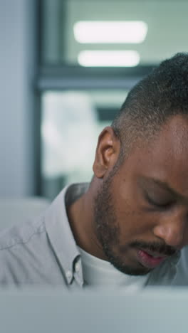 Nervous-African-American-male-voter-chooses-which-presidential-candidate-to-vote-for-in-voting-booth,-looks-at-camera.-US-citizen-at-polling-station-during-Election-Day-in-the-United-States-of-America