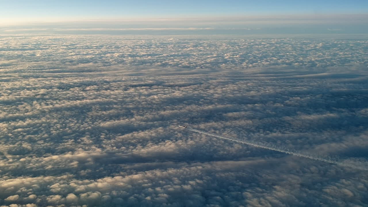 vista increíble desde la cabina de un avión que vuela alto por encima de las nubes dejando un largo rastro de aire de vapor de condensación blanco en el cielo azul