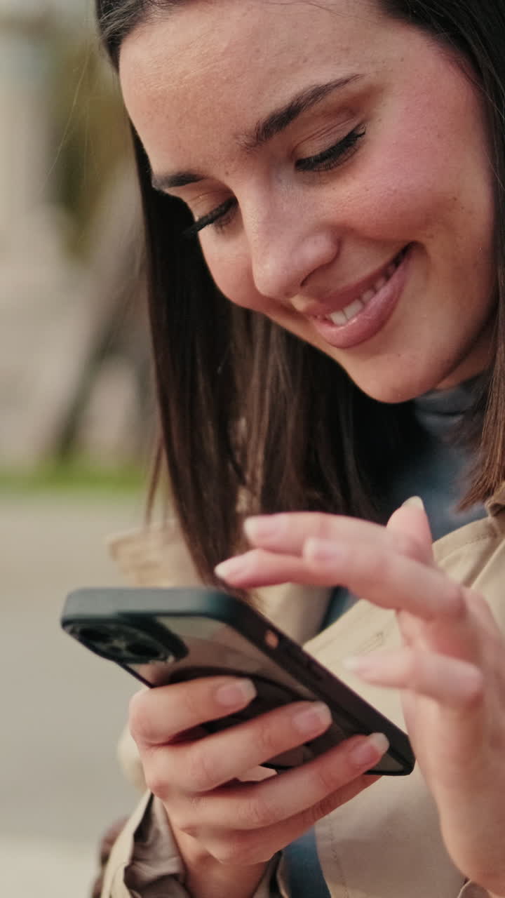 Giovane donna sorridente mentre usa lo smartphone all'aperto