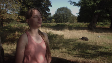 A-young-woman-taking-deep-breathe-under-the-shade-of-tree-with-sun's-ray-falling-on-her-face