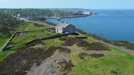 abandoned amlwch coastal countryside mountain house aerial pull away view overlooking anglesey harbour