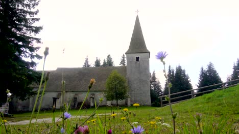 time lapse, dramatic clouds above alpine church and meadow with flowers in front, trije kralji, pohorje, slovenia