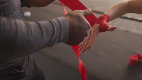 video de manos de diversas mujeres y hombres atando cintas, preparándose para el entrenamiento de caja en el gimnasio