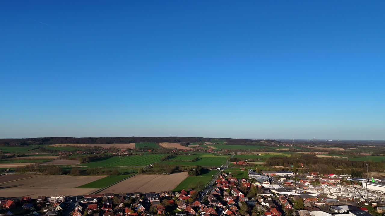 Clear blue sky and sunlight over hilly farm fields in american countryside. Small american town with houses and homes in USA. Drone Panorama wide shot. Quiet and peaceful landscape during spring.