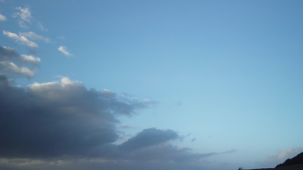 Hyperlapse of clouds rushing past as the sun is about to rise, blue hour, light reflecting on the clouds