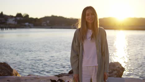 Blonde-woman-stands-on-the-stone-coast-smiling-happily