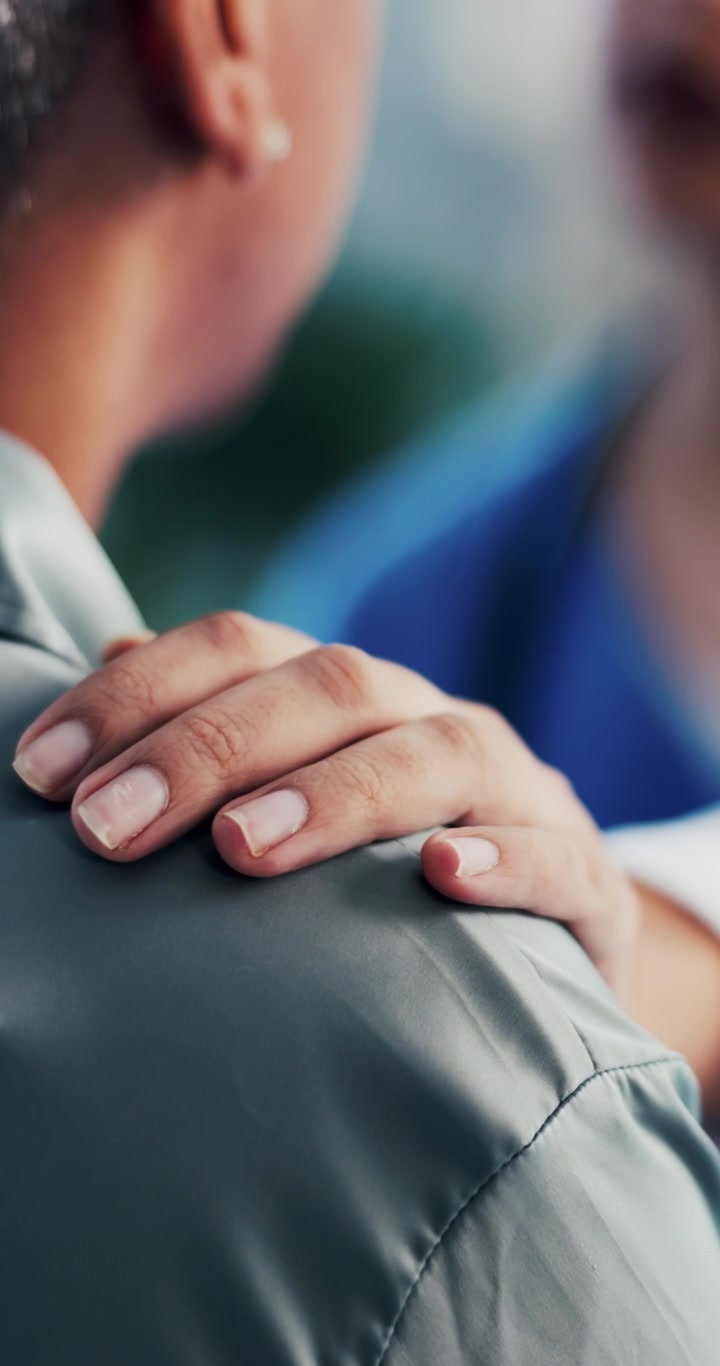 Primo piano di una persona che appoggia una mano sulla spalla di un'altra persona