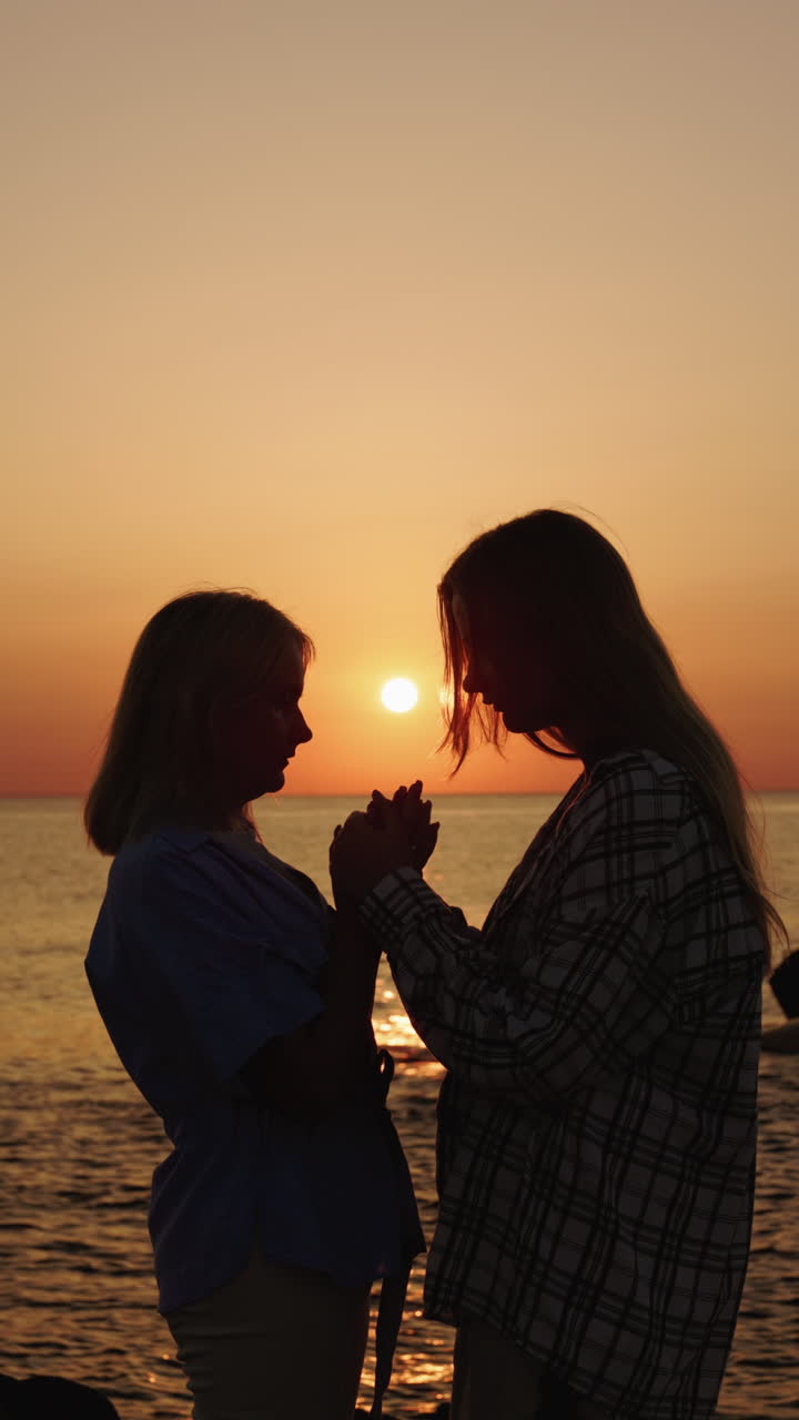 Two women holding hands at sunset