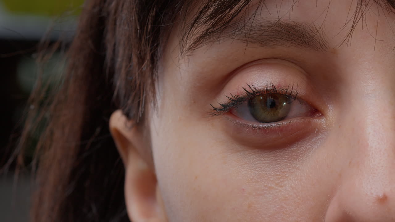 Macro shot of one green eye and half face in front of camera