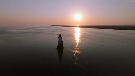 slow approach to lonely abandoned lighthouse in calm tidal waters at sunset. plover scar lighthouse, lancashire, uk.