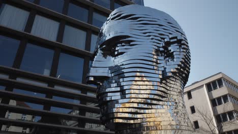 tilt up shot of iconic statue of kafka installed outside quadrio shopping centre, prague, czech republic