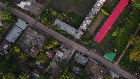 Aerial-top-down-view-of-car-travelling-along-road-through-slum,-Sylhet