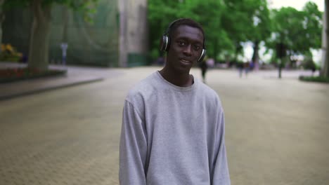 Cámara-Lenta-De-Un-Tipo-Alegre-Con-Ropa-Informal-Bailando,-Moviéndose-Libremente-Con-Auriculares-Al-Aire-Libre-Divirtiéndose-Solo-En-La-Ciudad,-Sonriendo,-Despreocupado-1