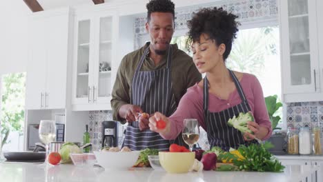 feliz pareja afroamericana cocinando y bebiendo vino en la cocina