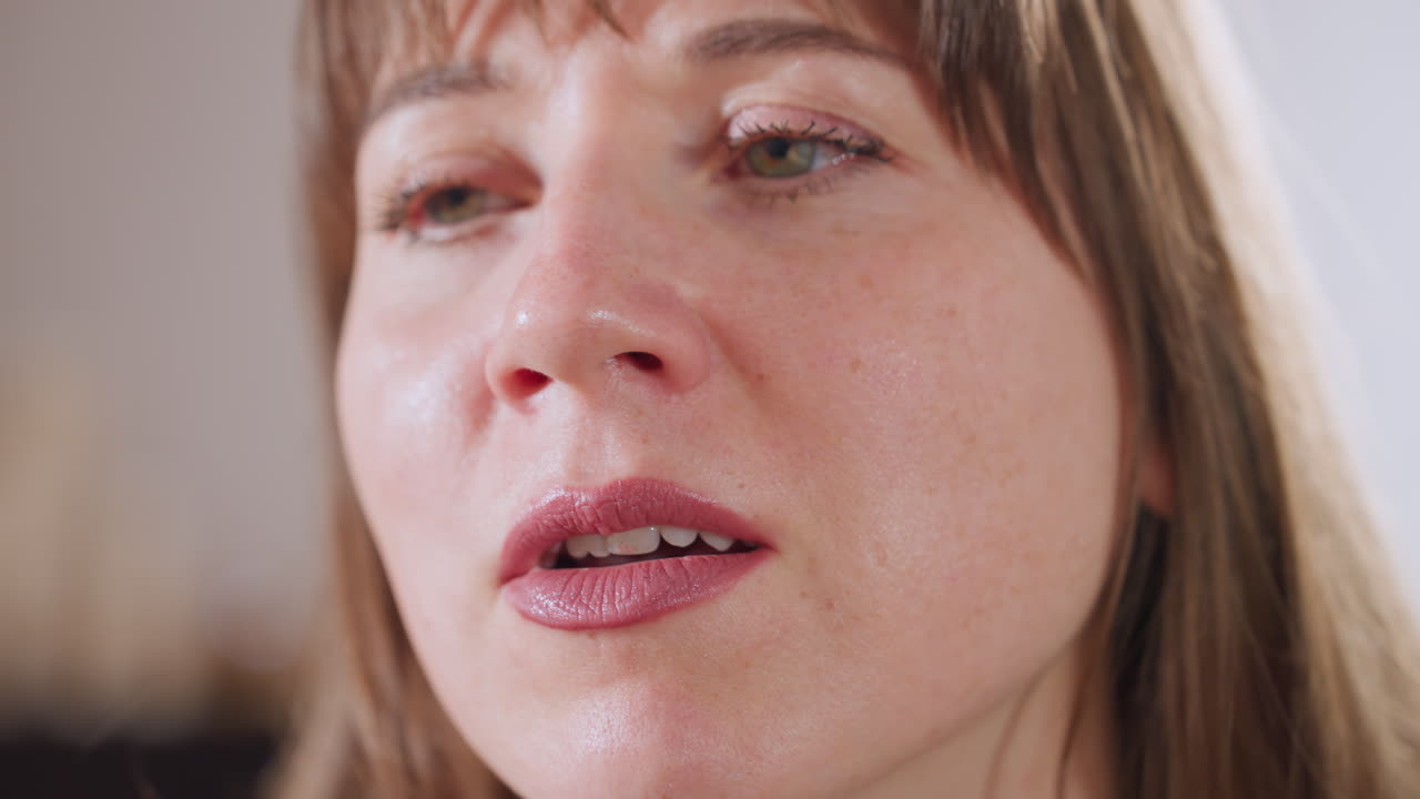 Close up view of restorative practitioner speaking with calm expression and gentle voice as facial detail and lip movement captured, conveying empathy and professionalism in quiet therapeutic setting