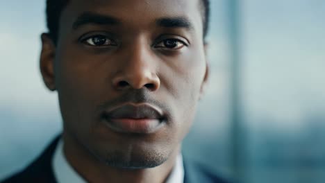 close up of a young businessmans face, confidently looking at the camera with a serious expression in a corporate setting